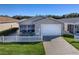 Tan house with white picket fence, landscaping and driveway at 409 Rose Croft Ter, The Villages, FL 32162