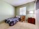 Cozy bedroom with a wicker chair, window, and neutral-toned decor at 5050 Cape Hatteras Dr, Clermont, FL 34714