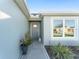 Front entry with gray door, decorative walkway, and potted plants at 6714 Newell Loop, The Villages, FL 34762