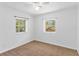 Bright bedroom with neutral carpeting and two windows at 13724 Country Club Dr, Tavares, FL 32778
