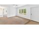 Living room with large window, neutral carpeting, and access to other rooms at 13724 Country Club Dr, Tavares, FL 32778
