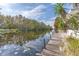 Serene waterfront view with wooden dock and lush vegetation at 13724 Country Club Dr, Tavares, FL 32778