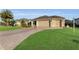 Tan house with a two-car garage and curved driveway at 1494 Walnut Way, The Villages, FL 32163