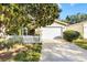 Cute yellow house with white picket fence, attached garage, and nicely landscaped yard at 2102 Estevez Dr, The Villages, FL 32159