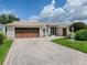 Single-story home with a two-car garage and landscaped yard at 25000 Riverwalk Dr, Leesburg, FL 34748