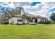 Back of house, white stucco, tile roof, and green lawn at 38230 Yale Cir, Leesburg, FL 34788