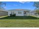 Home's backyard view with covered patio, green grass, and trees at 5047 Meadow Song Dr, Okahumpka, FL 34762