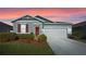 Single-story home with gray siding, red shutters, and a two-car garage at 5047 Meadow Song Dr, Leesburg, FL 34748