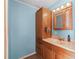 Bathroom with light blue walls, wood vanity, and a large mirror at 712 Tarrson Blvd, The Villages, FL 32159