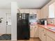 Kitchen area with black refrigerator and pinkish countertops at 712 Tarrson Blvd, The Villages, FL 32159