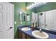 Bathroom with double sinks, blue countertop, and green walls at 14701 Timucua Pl, Clermont, FL 34711