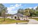 Single-story home with a gray roof, light beige walls, and palm trees at 14701 Timucua Pl, Clermont, FL 34711