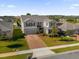 Aerial view of a two-story house with a gray exterior, brick driveway and landscaping at 1150 Blarney St, Minneola, FL 34715