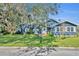 Charming blue house with white trim, surrounded by lush landscaping and mature oak trees at 214 S Woodland St, Winter Garden, FL 34787