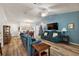 Open concept living room with teal sofas, hardwood floors, and a view into the dining area at 4414 Cameo Cir, The Villages, FL 32163