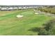 Aerial view of a putting green with sand traps and residential homes nearby at 840 Pebble Beach Dr, Davenport, FL 33896
