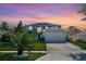 Two-story house with a gray exterior, white garage door, and landscaping at sunset at 1087 Welch Hill Cir, Apopka, FL 32712