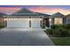 Home exterior at sunset with two-car garage and front yard landscaping at 3974 Towana Loop, The Villages, FL 32163