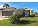 Tan one-story house with a two-car garage and well-manicured lawn at 5032 St. Andrews Arc, Leesburg, FL 34748