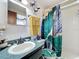 Well-lit bathroom featuring a teal shower curtain and green vanity at 316 Amanda Ln, Leesburg, FL 34748