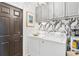 Bright laundry room features washer, dryer, and stylish gray cabinets at 6147 Spinnaker Loop, Lady Lake, FL 32159