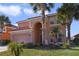 Two-story house with a pink facade, a three-car garage, and palm trees at 151 Rubino Dr, Davenport, FL 33837