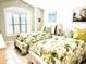 Bright bedroom with two twin beds, plantation shutters, and tropical decor at 2850 Apache Ct, The Villages, FL 32163