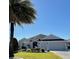 Beautiful single-story home with a gray exterior, lush landscaping, and a three-car garage at 2850 Apache Ct, The Villages, FL 32163