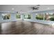 Spacious living room with light blue walls, wood-look floors, and multiple windows at 3550 Auburndale Ave, The Villages, FL 32162