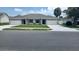 Front exterior of a duplex with gray siding, white garage doors, and a landscaped yard at 435 Woodview Dr, Tavares, FL 32778