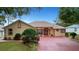 Single-story home with a red door, large driveway, and landscaped yard at 5509 Grove Mnr, Lady Lake, FL 32159