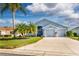 Two-car garage, light gray house with palm trees and manicured lawn at 5717 Illumination Ln, Leesburg, FL 34748