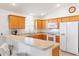 Kitchen with light oak cabinets, white appliances, and a breakfast bar at 893 Parrish Pl, The Villages, FL 32163