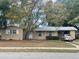 Tan single story house with a carport and mature trees in the front yard at 1122 E Hancock Dr, Deltona, FL 32725