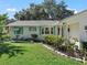 White single story home with teal accents and lush landscaping at 1310 Moray Ct, Leesburg, FL 34788