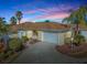 Charming single-story home with attached garage, landscaped yard, and palm trees, under a vibrant sunset sky at 1500 Alexa Pl, The Villages, FL 32162