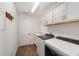 Laundry room with white cabinets, washer, dryer, and wood-look flooring at 3766 Causey Ct, The Villages, FL 32163