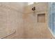 Clean bathroom with tan tile, a shower with grab bar, and a glass block window at 747 Bradford Loop, The Villages, FL 32163