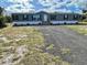 Mobile home with green siding and black windows, showcasing a gravel driveway at 9018 Atlas Dr, Saint Cloud, FL 34773