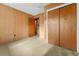 Bedroom with wood paneled walls, carpeted floor, and door to bathroom at 11451 Pala Verda Ave, Leesburg, FL 34788