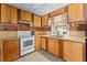 View of retro kitchen with wood cabinets and white appliances at 11451 Pala Verda Ave, Leesburg, FL 34788