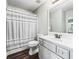 Bathroom with white vanity, shower with striped curtain, and wood-look floor at 11584 Se 175Th St, Summerfield, FL 34491