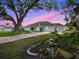 Front exterior of home illuminated in twilight, mature landscaping and trees at 11584 Se 175Th St, Summerfield, FL 34491