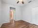 Empty bedroom with wood-look flooring, white closet, open door, and ceiling fan at 3556 Creek Run Ln, Eustis, FL 32736