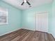 Light teal bedroom with wood-look flooring, white closet doors, and ceiling fan at 3556 Creek Run Ln, Eustis, FL 32736