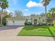 Green two-story home with a three-car garage, landscaped yard, and palm trees at 3556 Creek Run Ln, Eustis, FL 32736