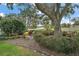 Landscaped backyard with a tranquil seating area under a large oak tree at 1281 Gray Ct, Eustis, FL 32726