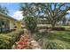 Landscaped backyard with stone path, lush foliage, and large oak tree at 1281 Gray Ct, Eustis, FL 32726