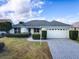 House exterior showcasing gray roof, light-yellow garage and manicured hedges at 1320 Arredondo Dr, The Villages, FL 32162