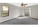 Bright bedroom with large windows, ceiling fan, and grey carpet at 13340 Country Club Dr, Tavares, FL 32778